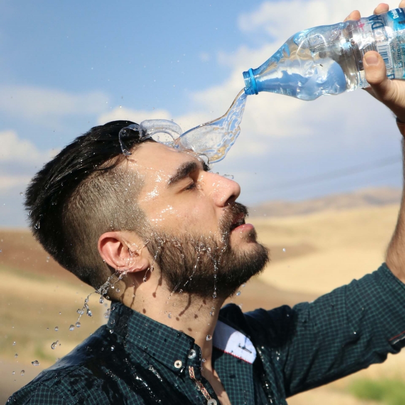 man splashing a bottle of water on his face