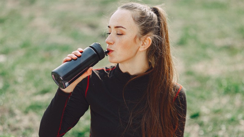 yoga girl drinks water in a summer park