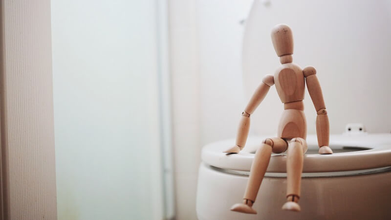 a tiny human sit on a toilet