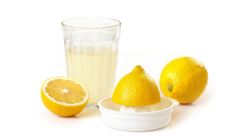 a glass of lemon juice and lemons