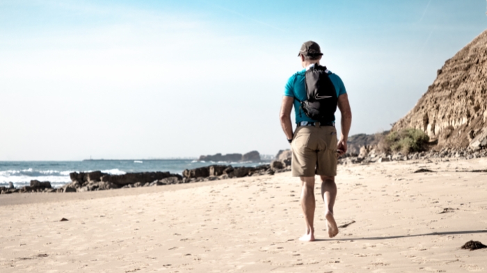 a man wear backpack on the beach